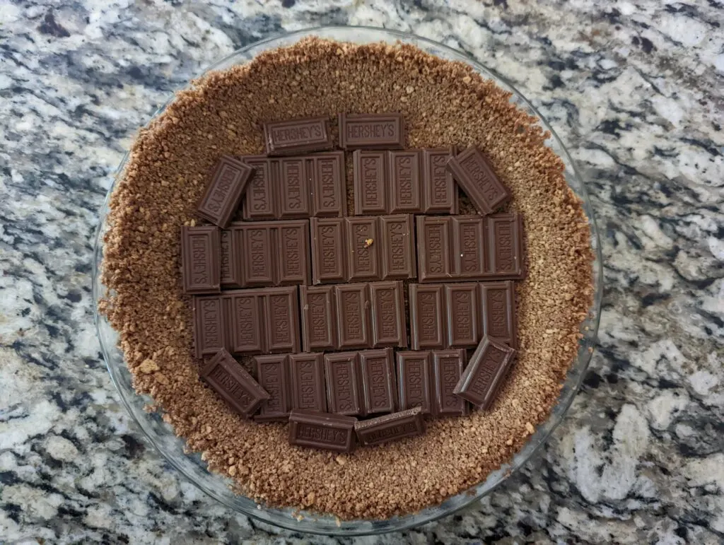 A layer of chocolate bars added to a pie tin.