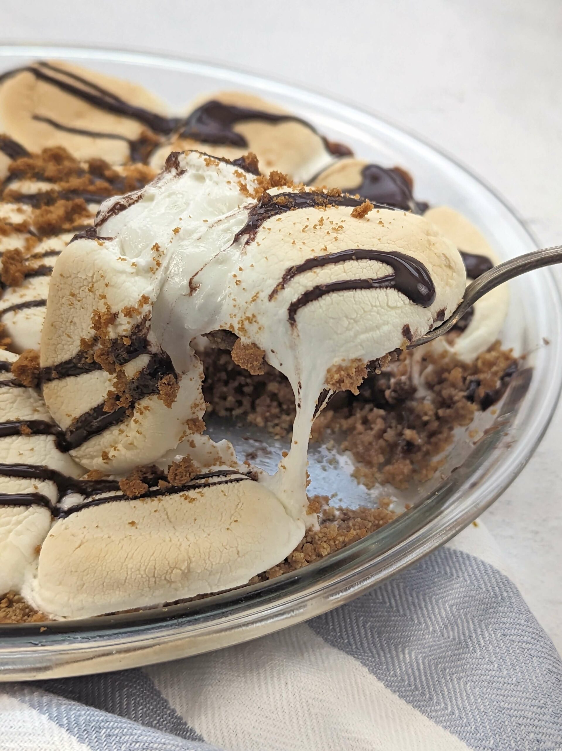 A scoop of smores pie drizzled with warm chocolate and sprinkled with graham crackers.