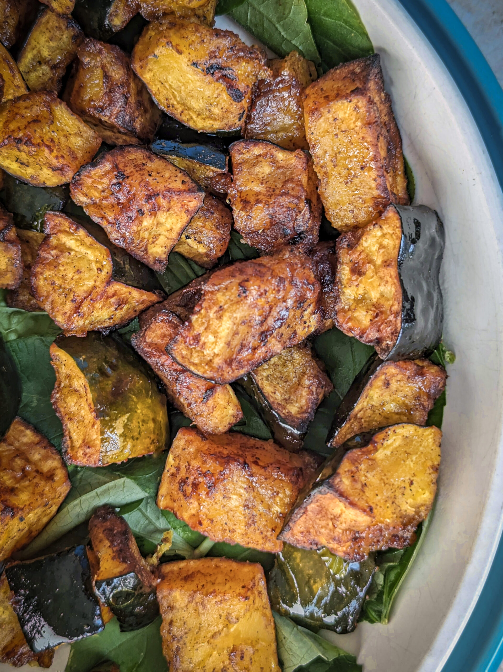 Air fryer acorn squash on a plate with chicken sausage and mixed greens.
