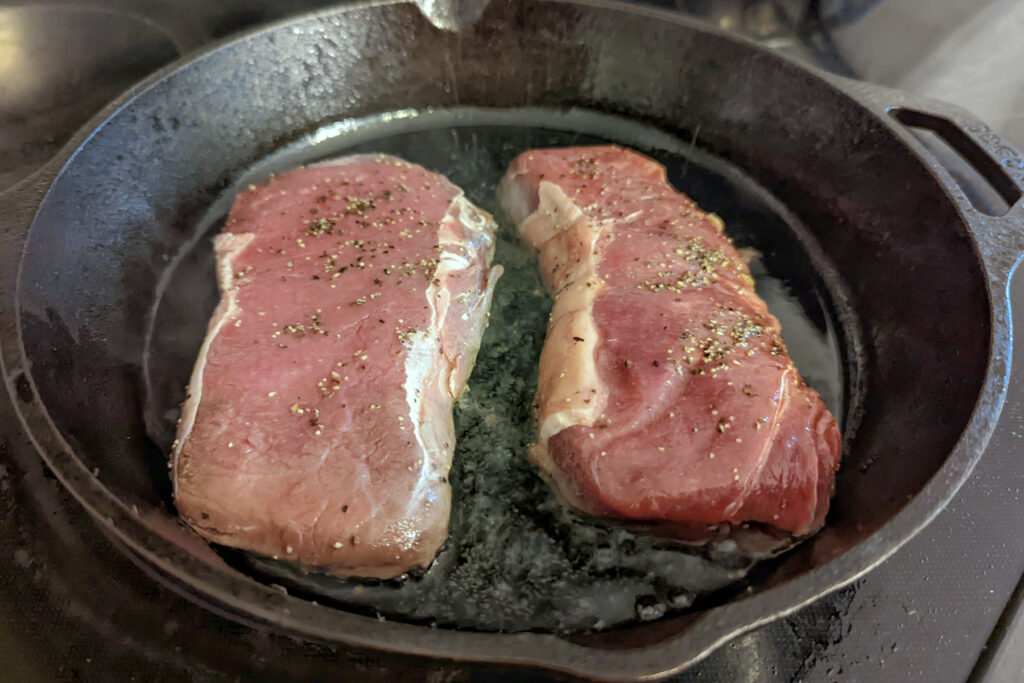 Bison searing in a cast iron pan.