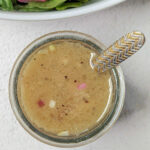 Sherry shallot dressing in a container in front of a salad.