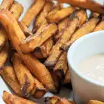 A close up of sweet potato fries and sauce.