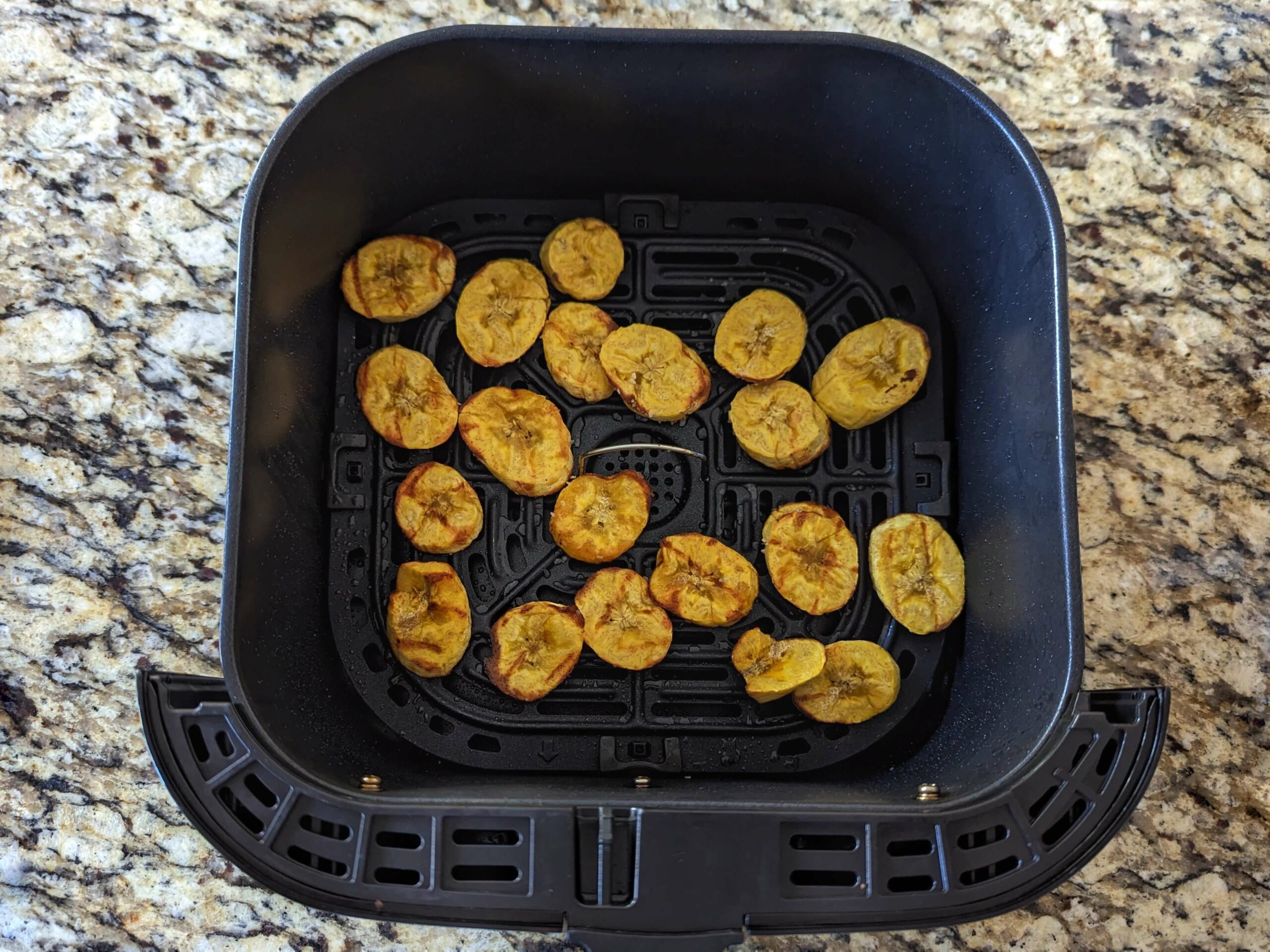 Plantains slices flipped and seared in the air fryer basket.