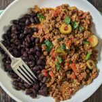 Beef picadillo on a plate black beans.