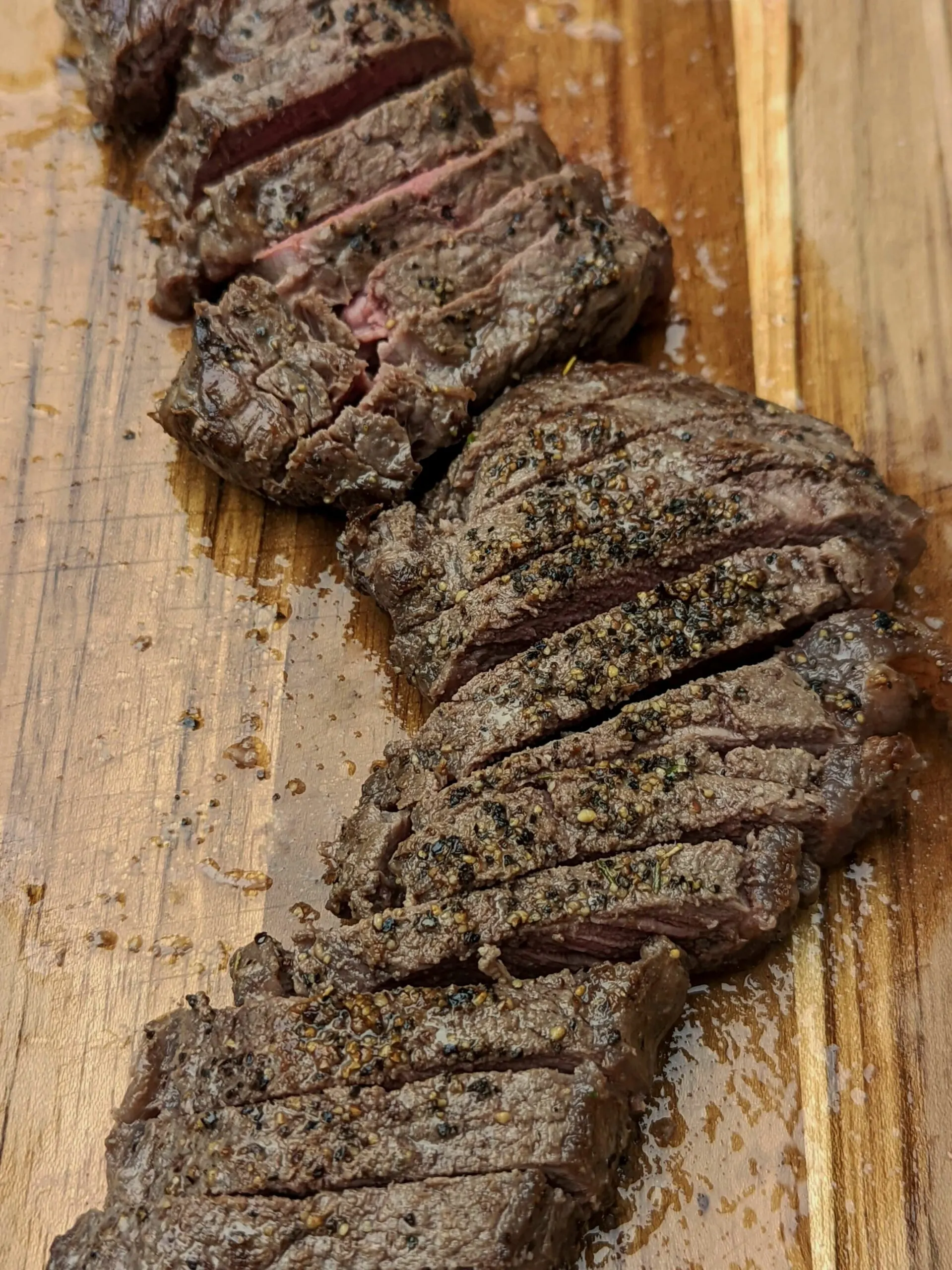 Bison steak on a cutting board and sliced into pieces.