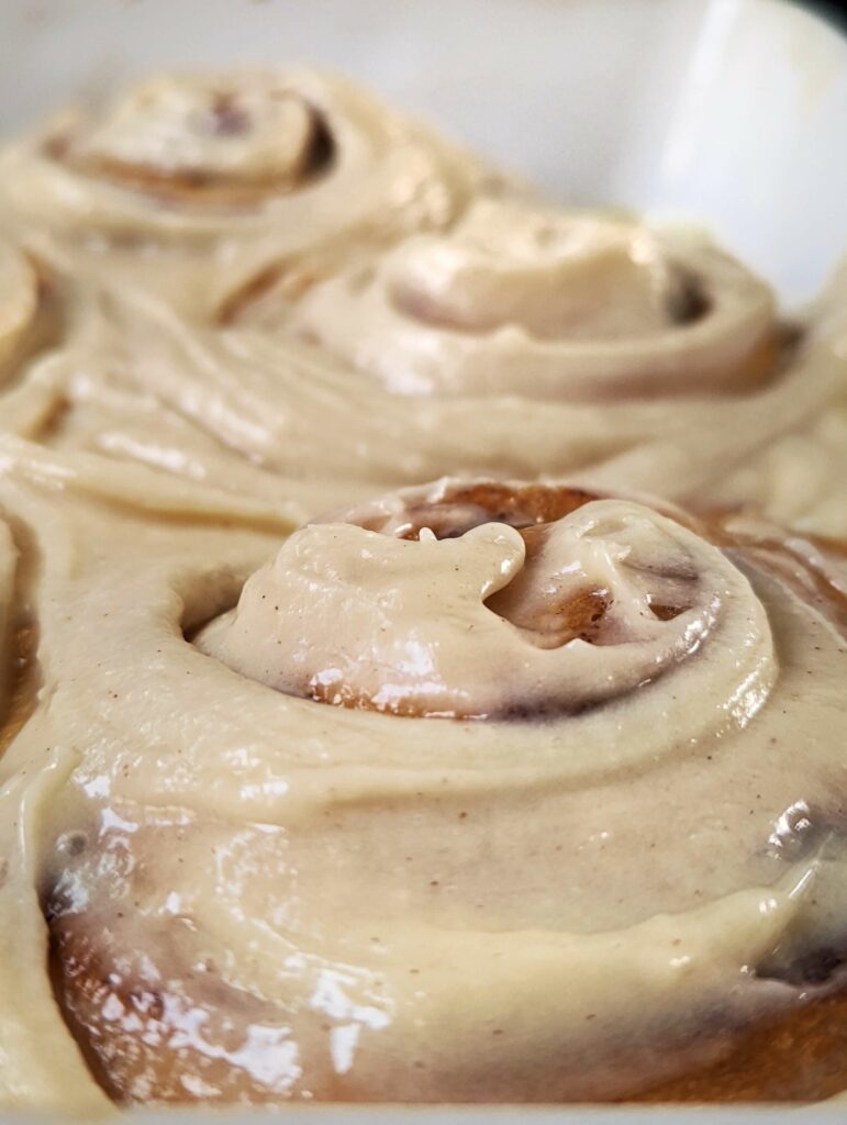 A close-up of two cinnamon rolls with cream cheese frosting.