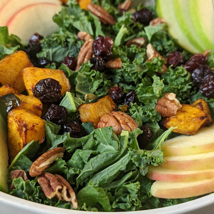 Fall Kale Salad on a plate with a side of dressing.
