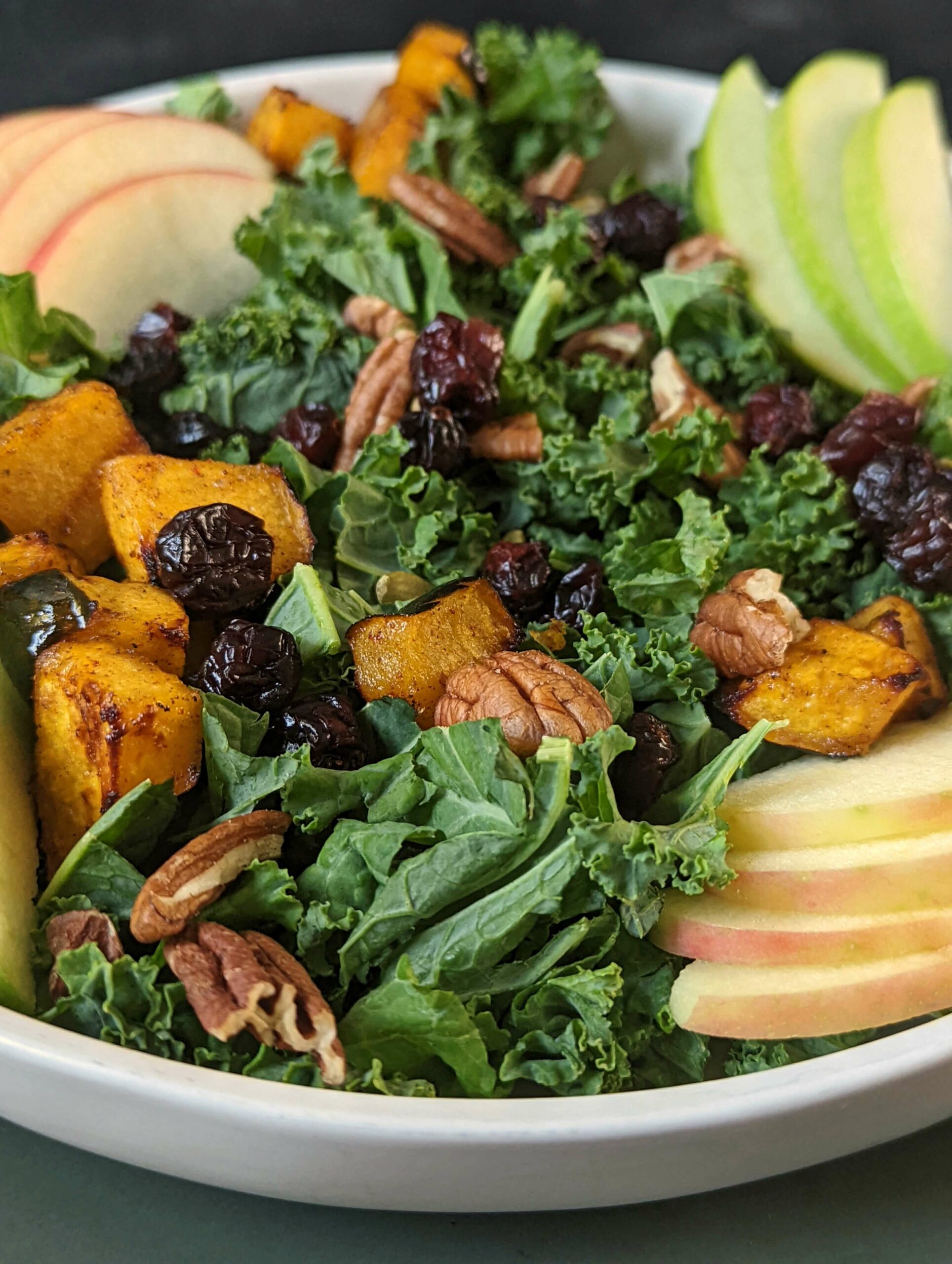 Fall Kale Salad on a plate with a side of dressing.