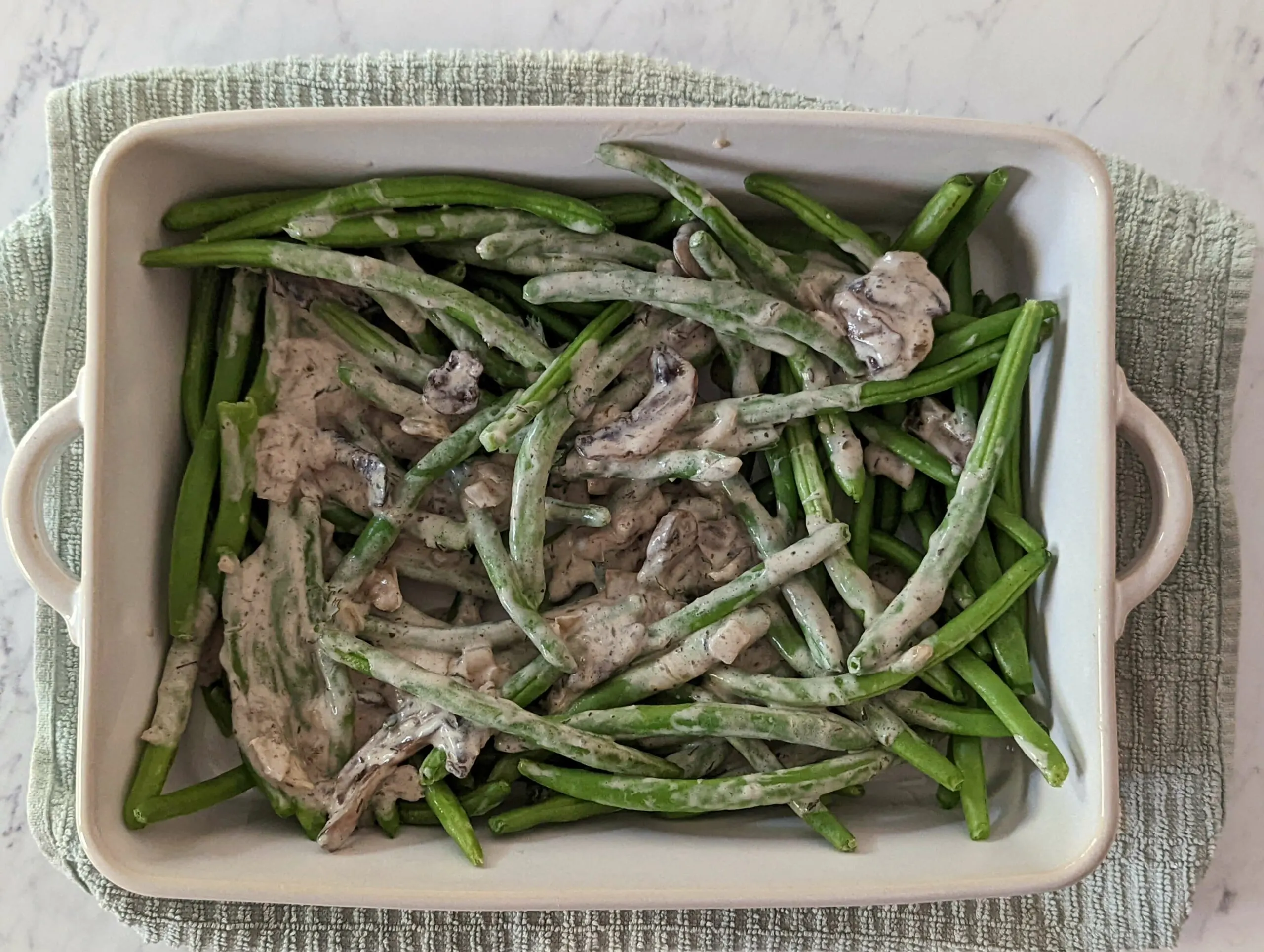 Green beans in a baking dish covered with cream of mushroom soup.