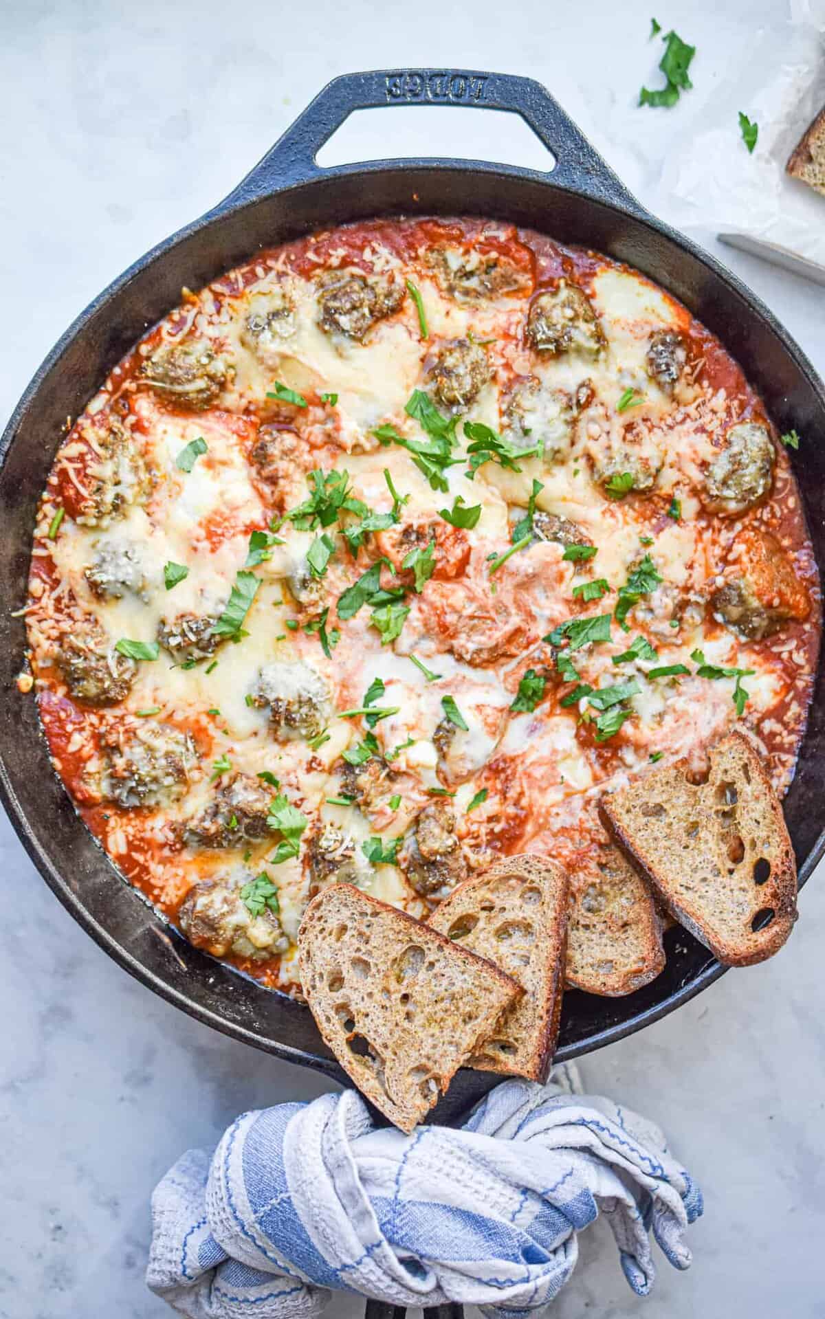 A skillet of homemade italian meatball sub dip topped with fresh herbs.