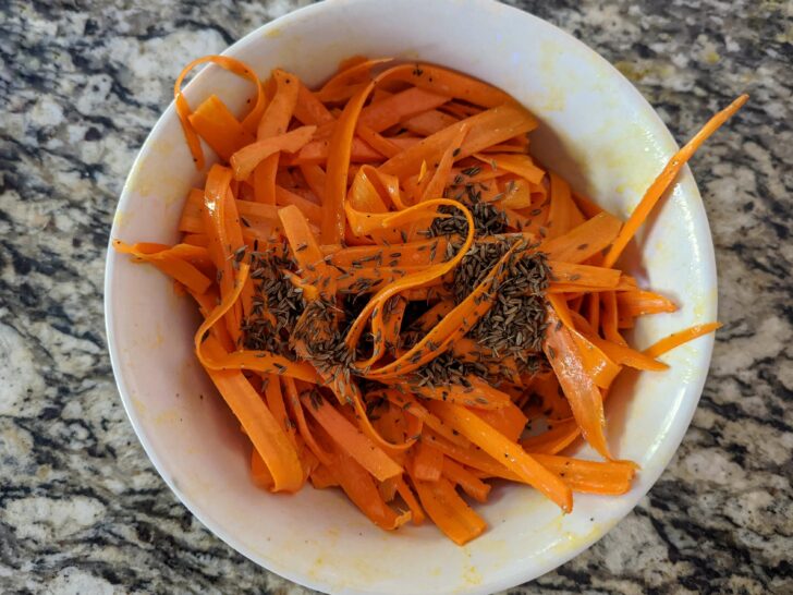 Carrots and dressing combined in a serving bowl.