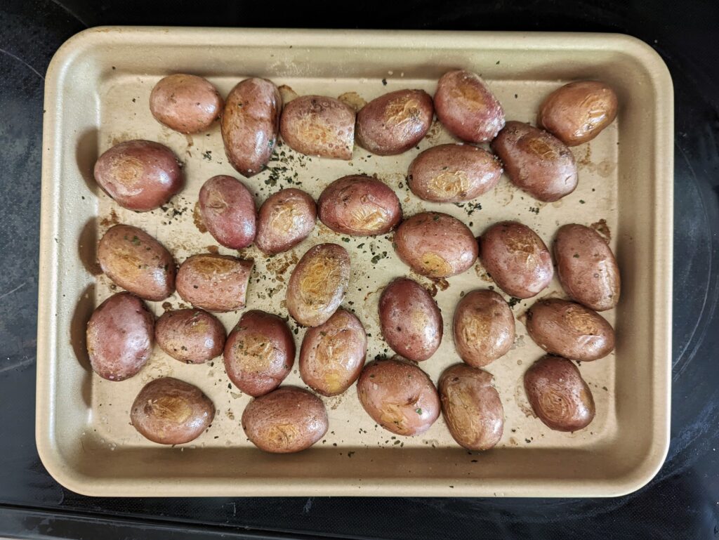 Season the potatoes with parsley, salt, and pepper and place them face down on the baking sheet to start.
