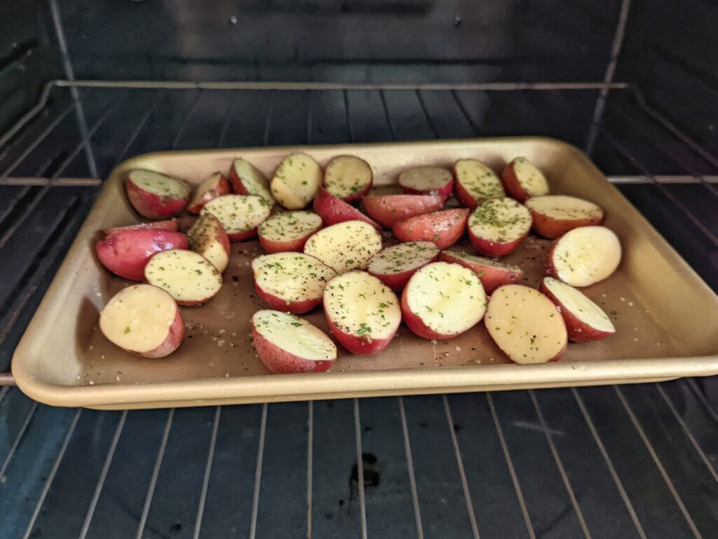 Potatoes on a rimmed baking sheet in the oven.