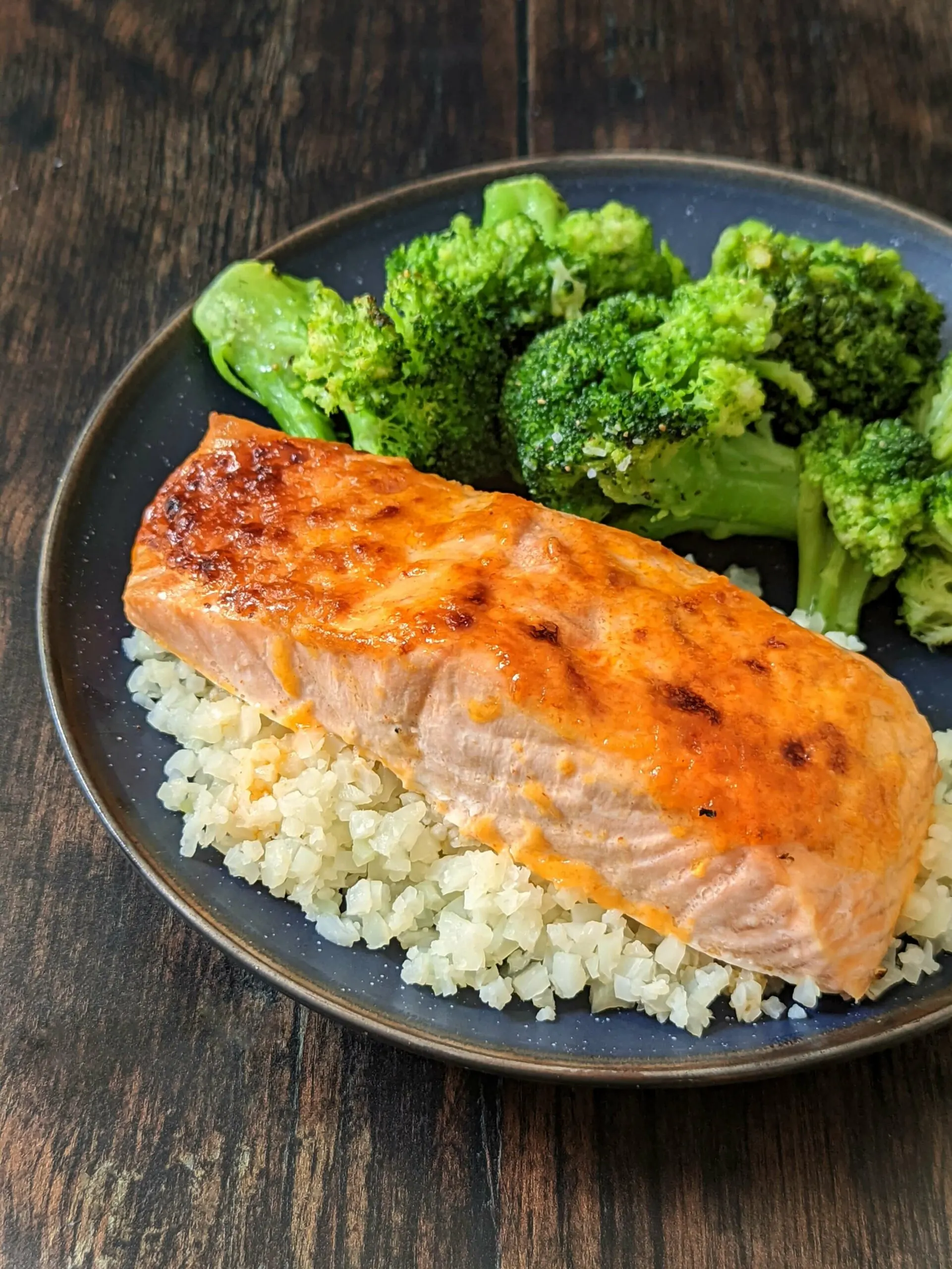 An overhead shot of Sriracha salmon over cauliflower rice and paired with roasted broccoli.