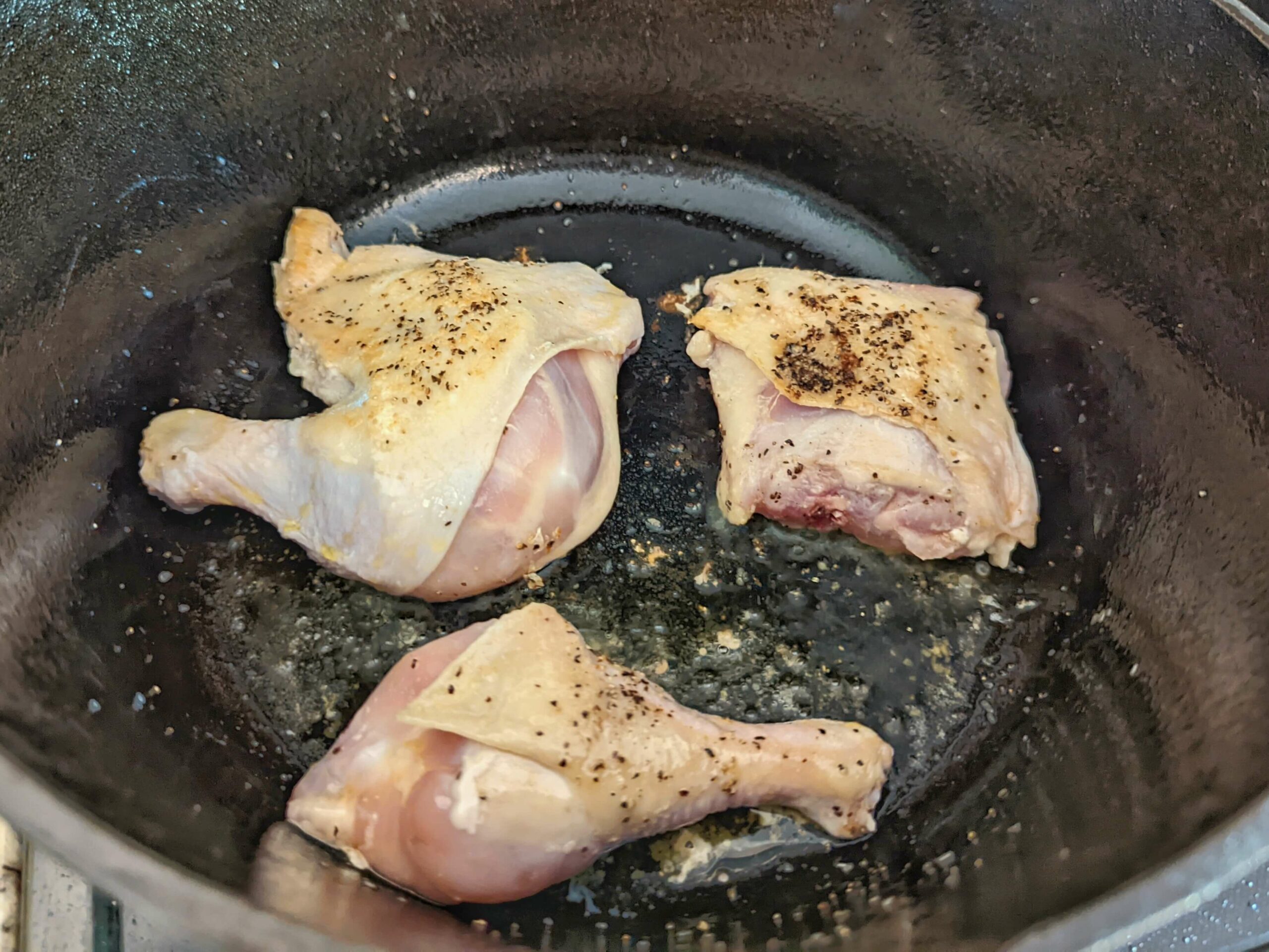Chicken quarters flipped in the Dutch oven.