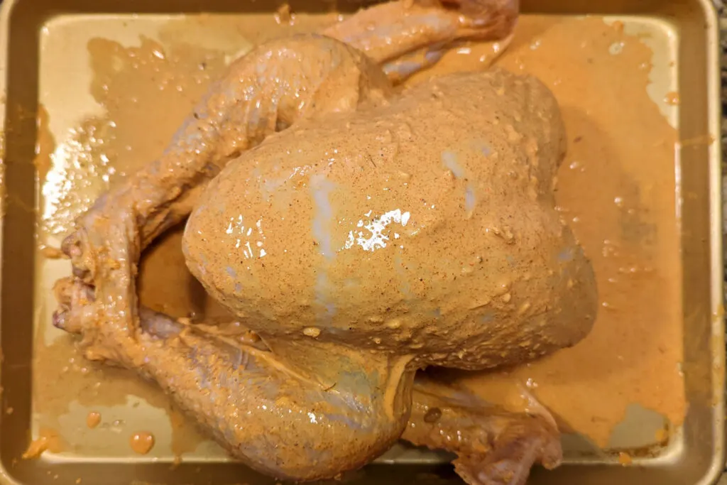 A uncooked turkey slathered in tandoori masala.