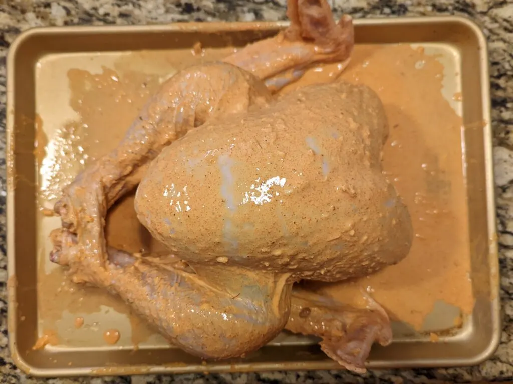 A uncooked turkey slathered in tandoori masala.
