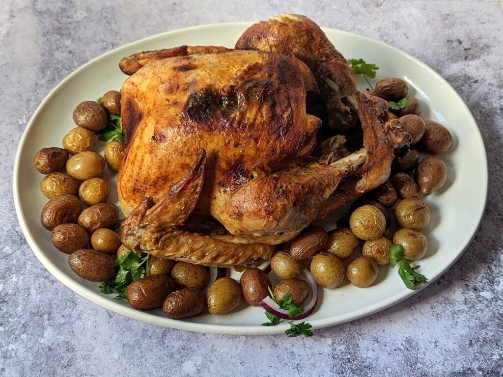 Tandoori turkey on a platter with roasted potatoes.