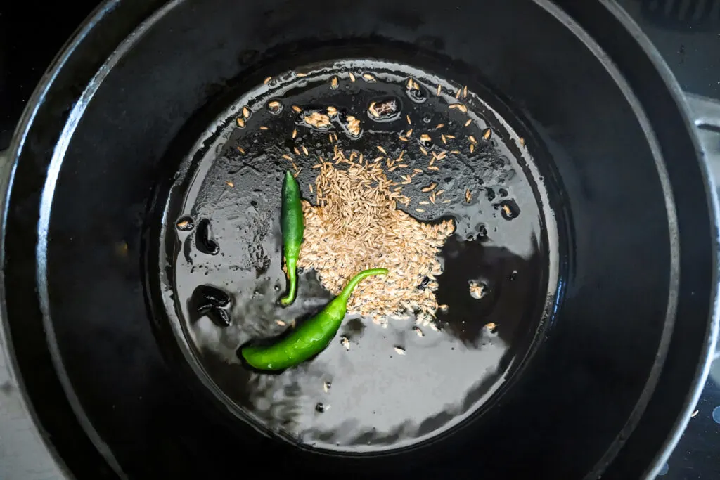 Whole spices and green chilies searing in the pan.
