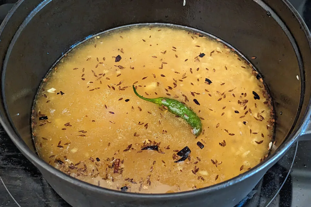 Yakhni, rice, and biryani masala added to the pan.