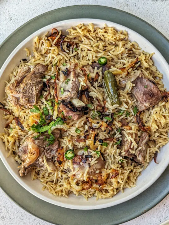 Yakhni pulao on a plate topped with cilantro.