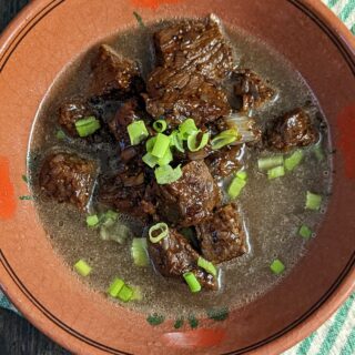 Tender beef pares served in a bowl with clear beef broth.