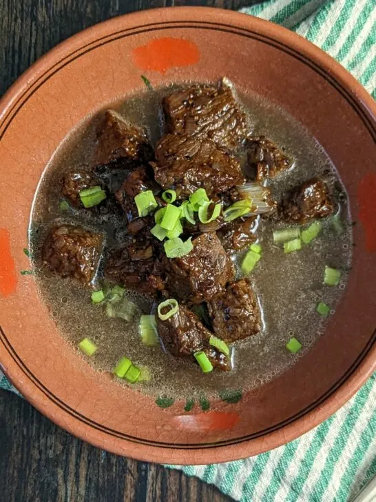 Tender beef pares served in a bowl with clear beef broth.
