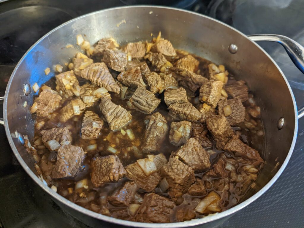Beef and remaining pares ingredients simmering in a pot.