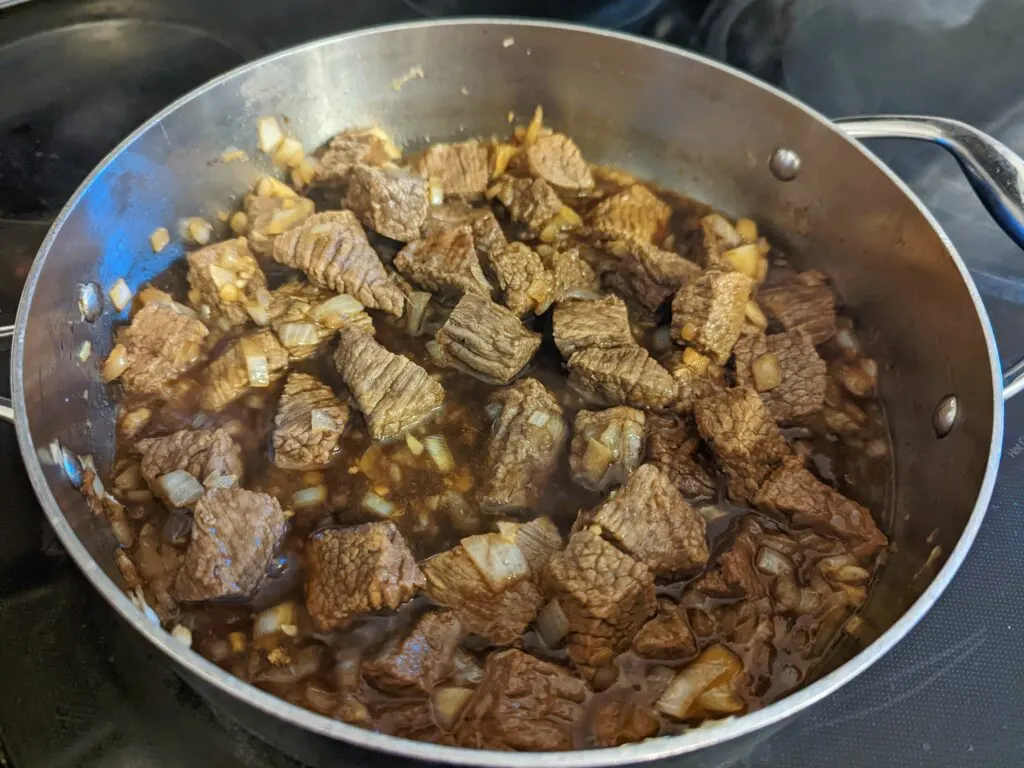 Beef pares ingredients simmering in a pot.