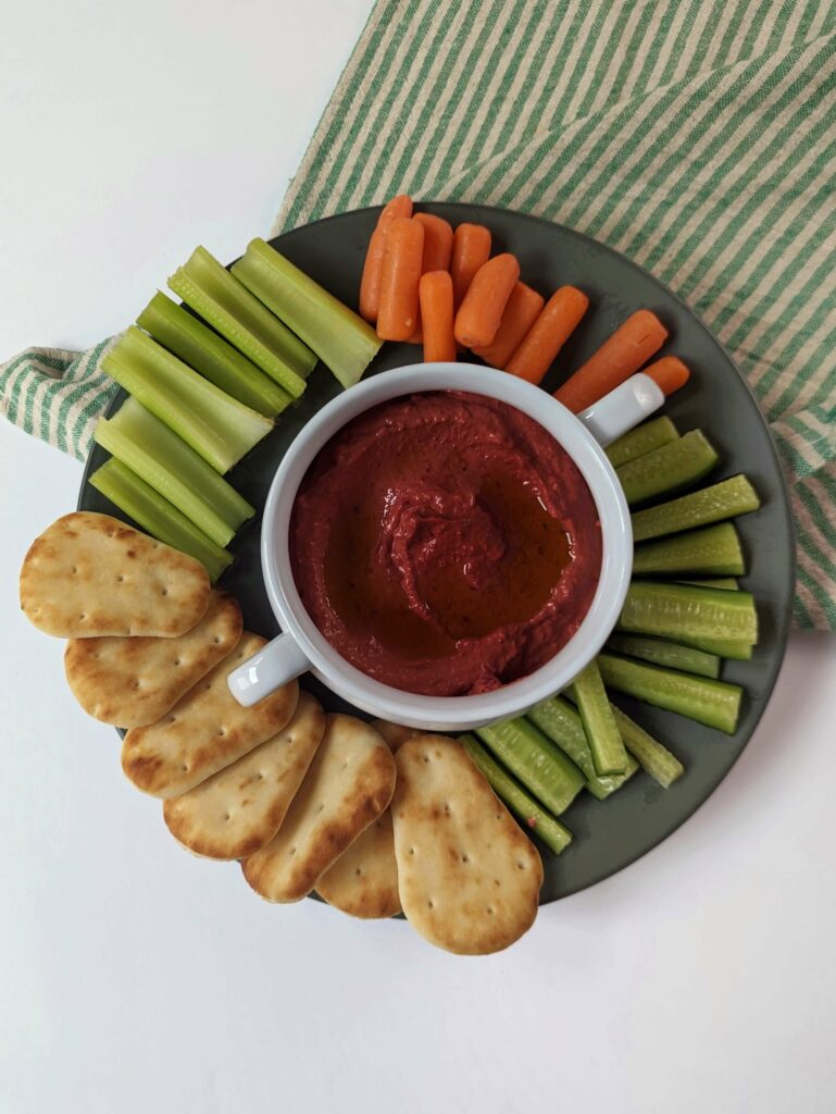 Beetroot dip surrounded by vegetables and naan bites.