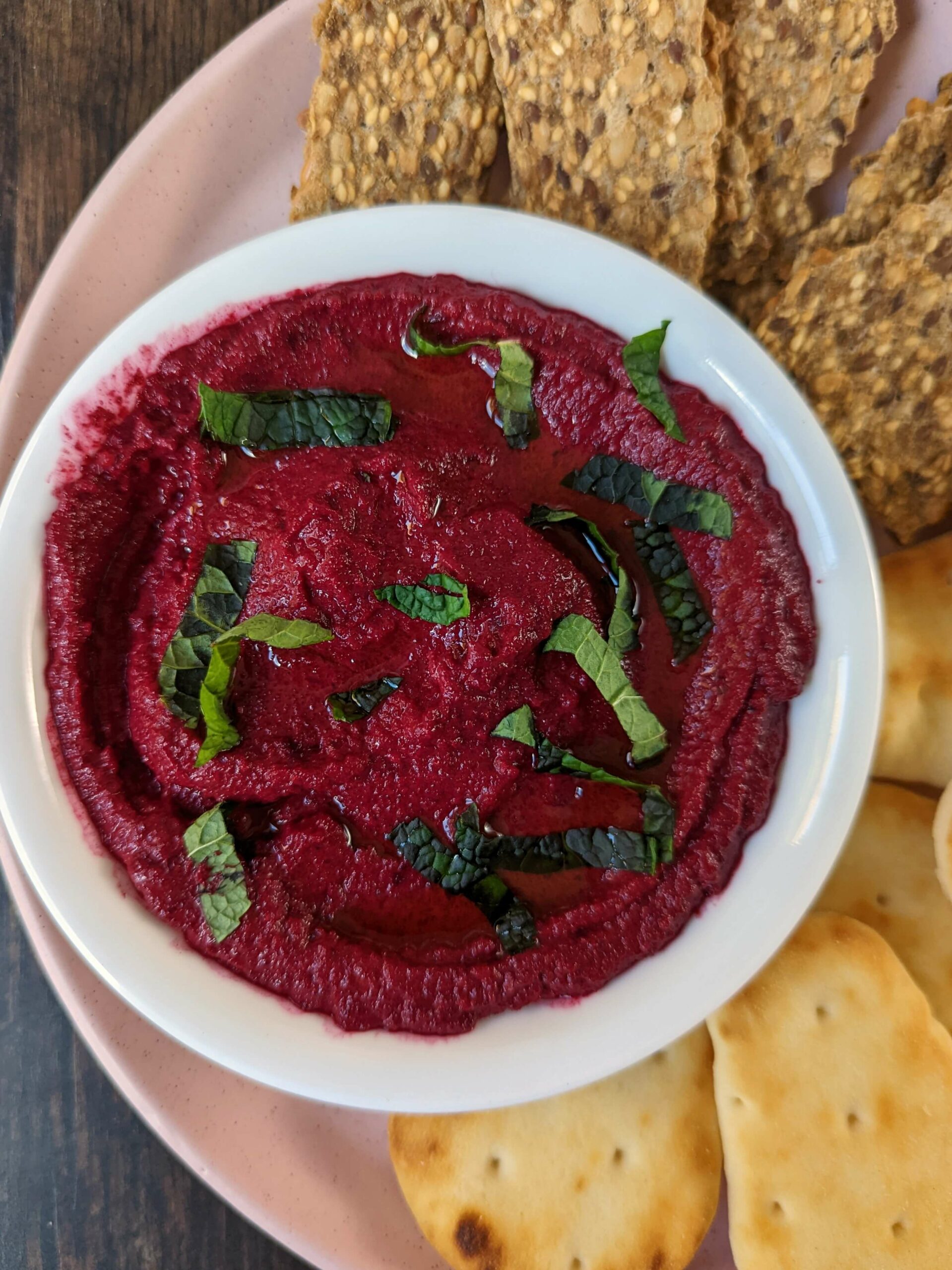 Beetroot dip surrounded by crackers and naan bites.