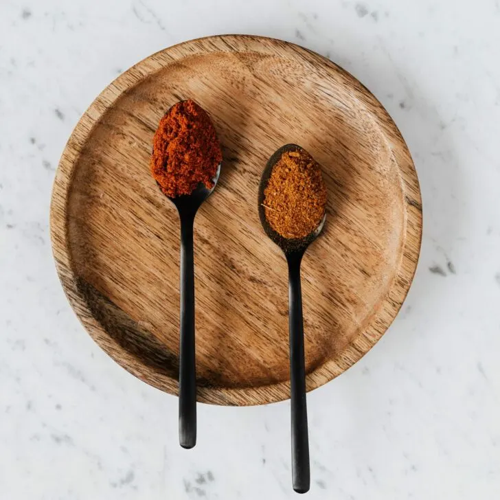 Different types of paprika on two spoons.