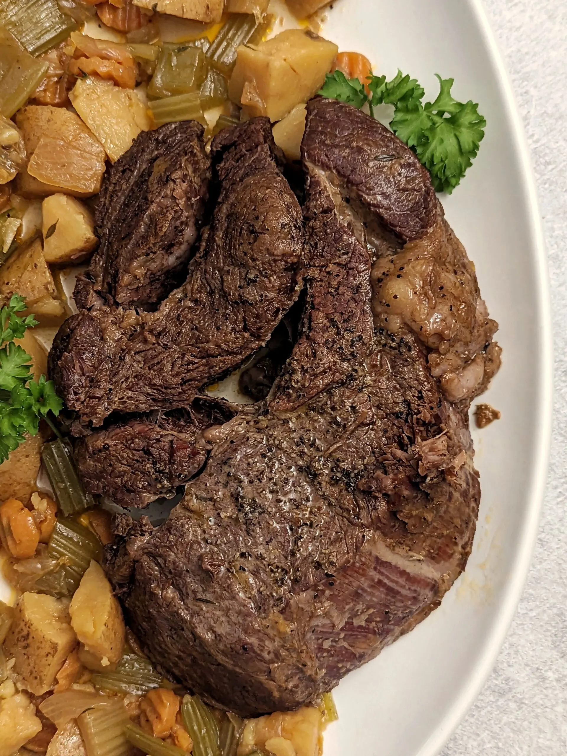 A whole pot roast surrounded by tender vegetables.