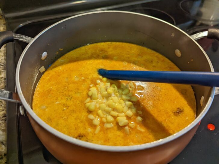 Corn and beans added to the chili in a Dutch oven.