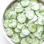 Cucumber salad in a bowl garnished with fresh dill.
