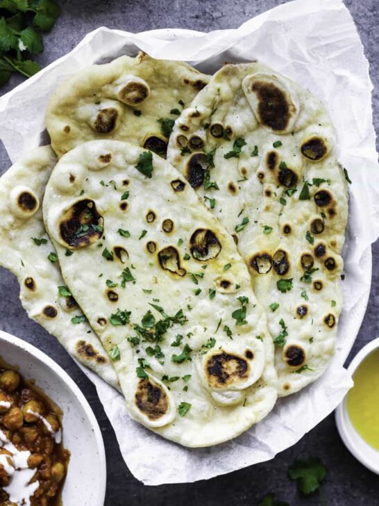 Naan on a plate with cilantro and butter on top.