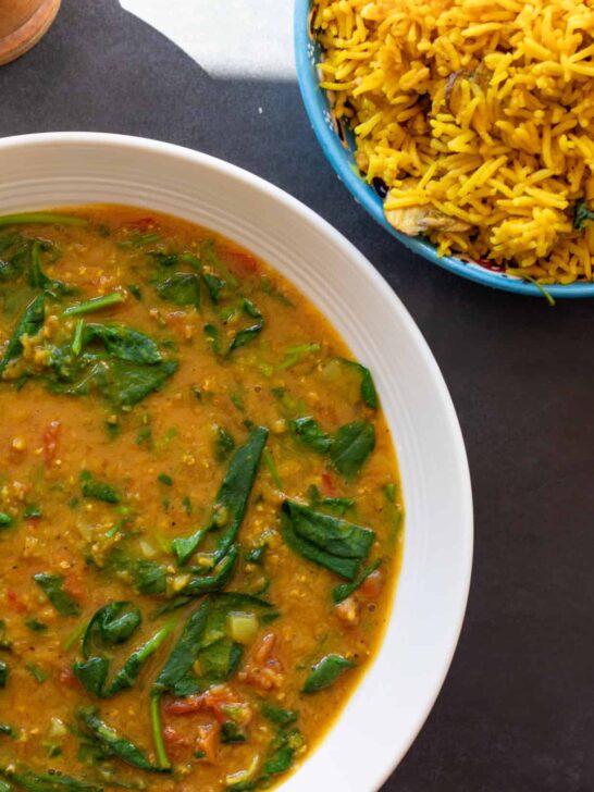 Spinach dal in a bowl with rice in the background.
