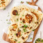 A plate of naan garnished with garlic butter and cilantro.