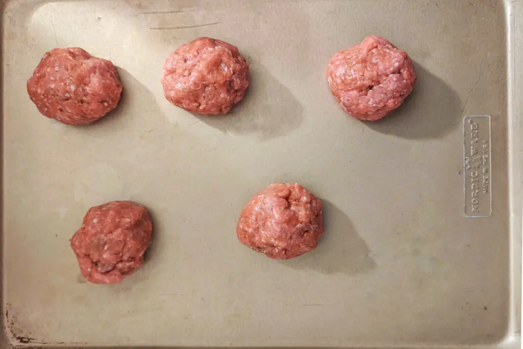 Turkey patties rolled into circles on a baking sheet.