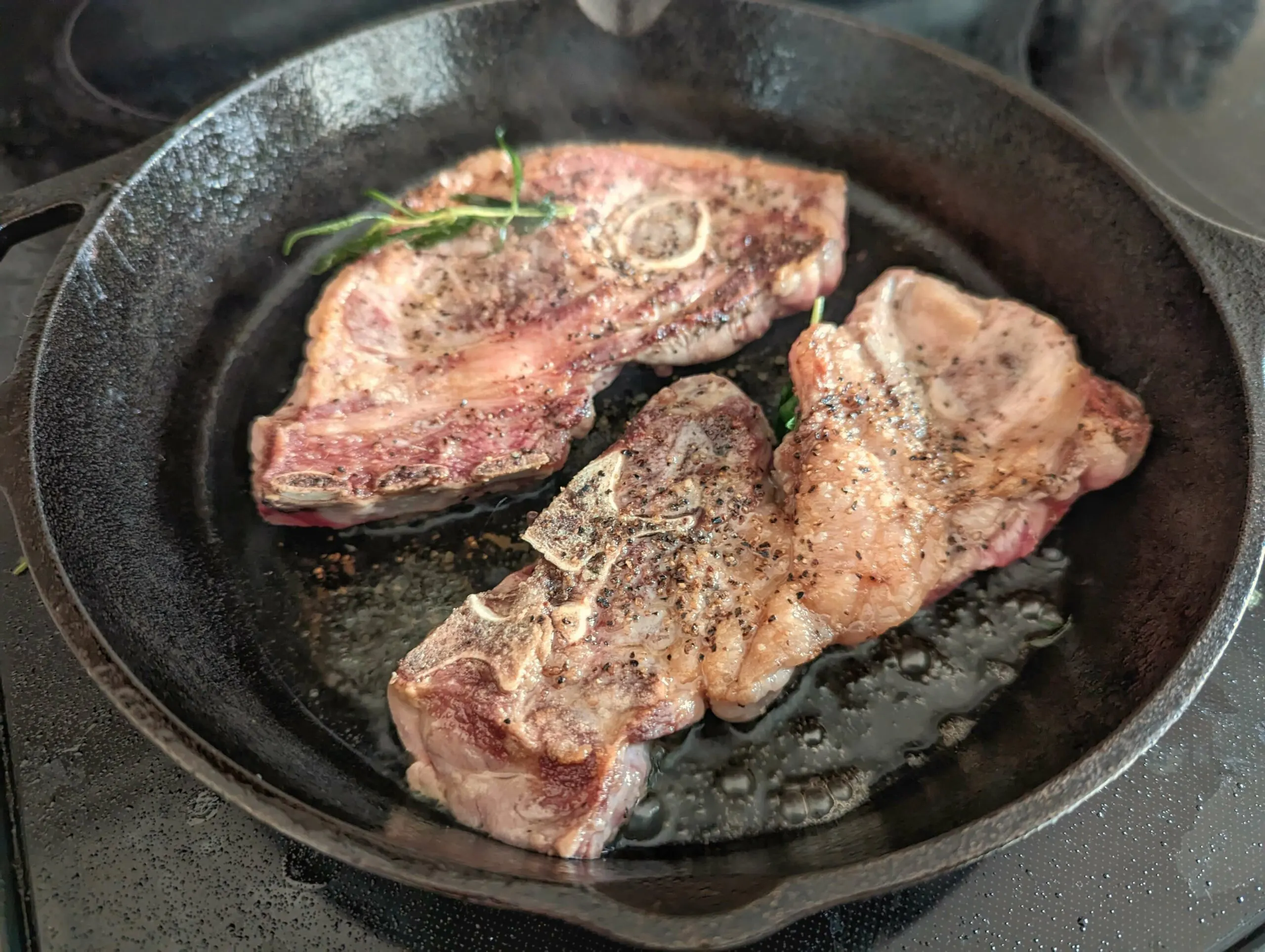 Lamb shoulder chops searing on a pan.