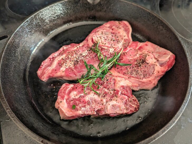 Lamb shoulder chops searing on a pan.
