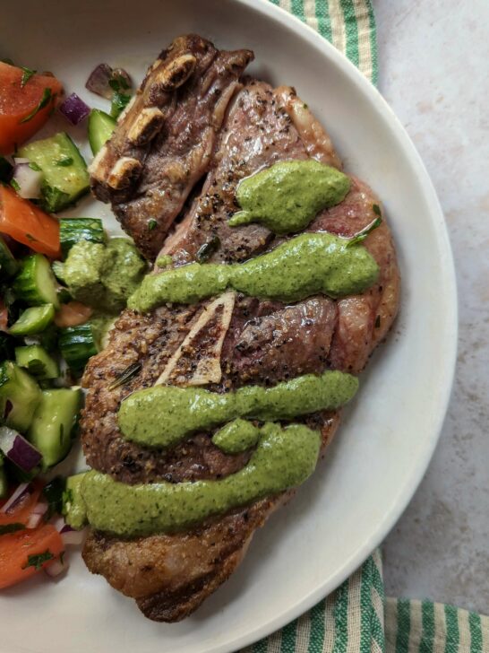 Lamb shoulder chop served with cucumber and tomato salad and topped with mint chutney.
