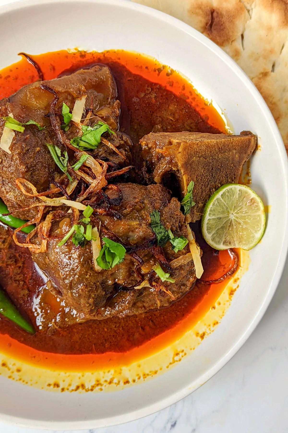 Nihari on a plate with naan.