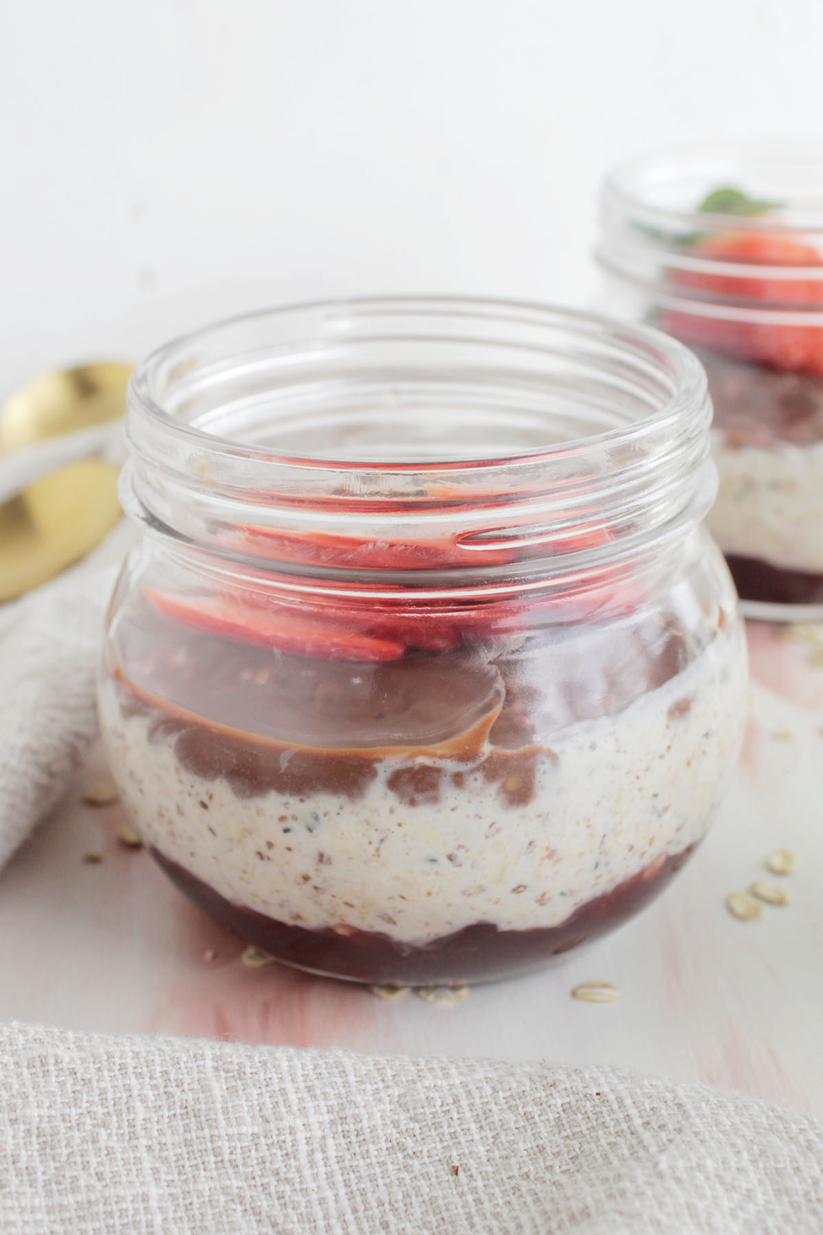 A container of overnight oats with chocolate and topped with fresh strawberries.