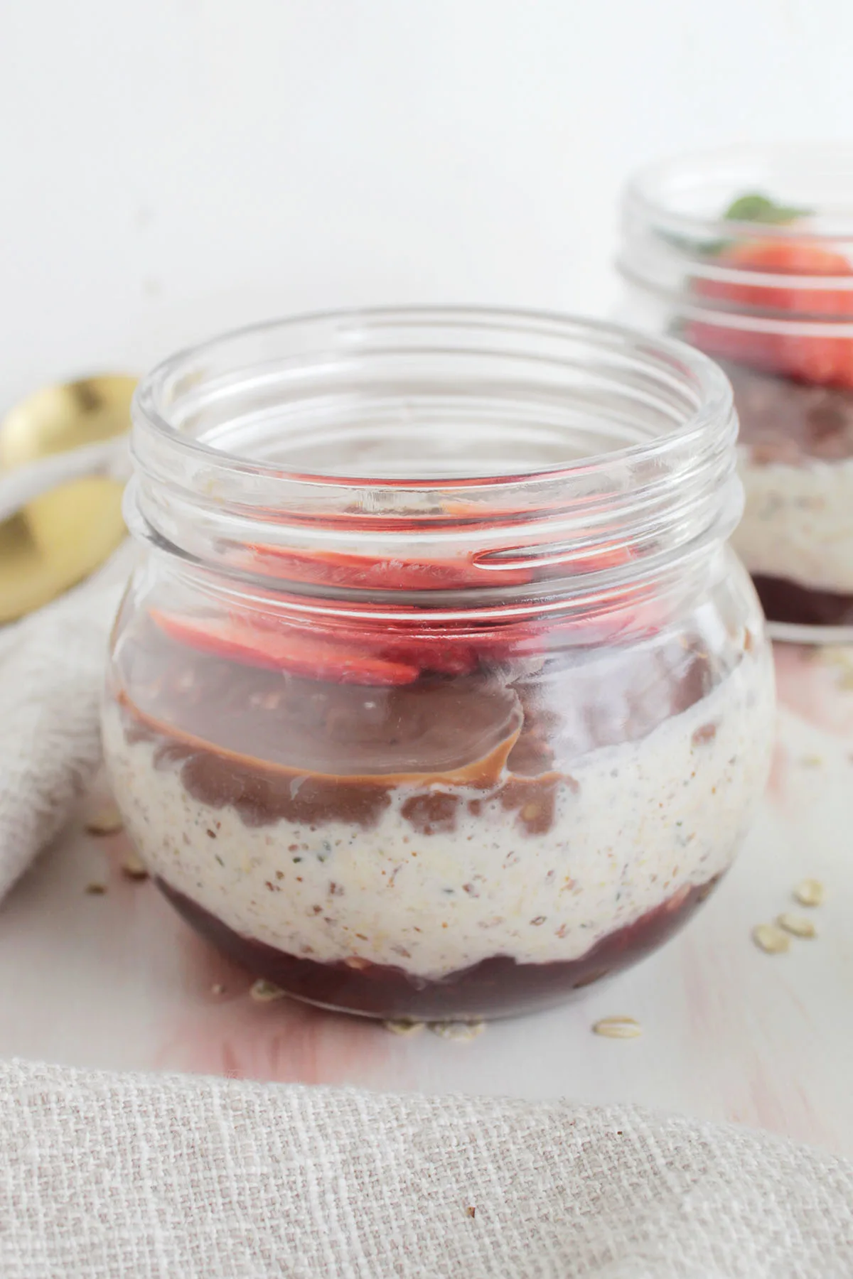 A container of overnight oats with chocolate and topped with fresh strawberries. 