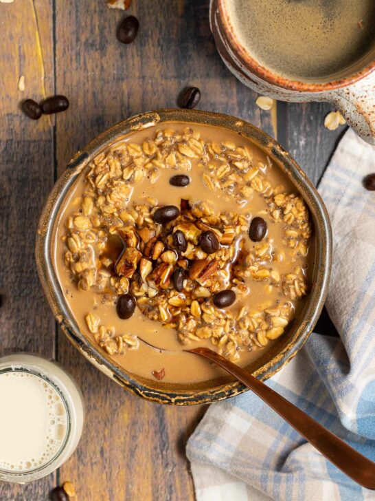 A container over coffee overnight oats topped with nuts and espresso beans. 