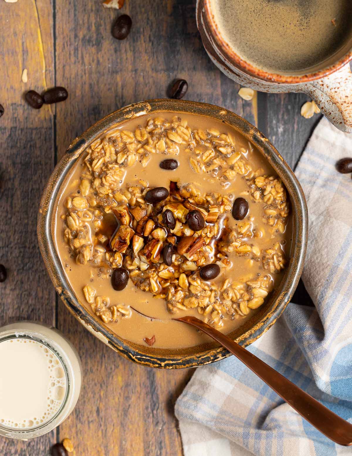 A container over coffee overnight oats topped with nuts and espresso beans. 