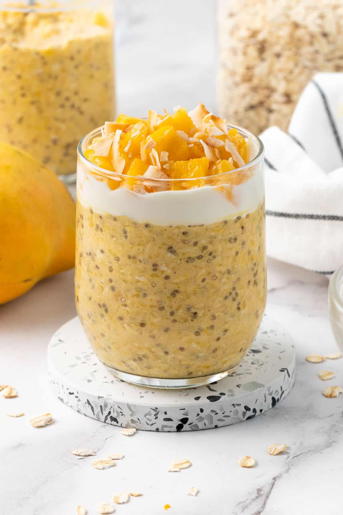 A jar of mango overnight oats topped with shaved mango slices. 