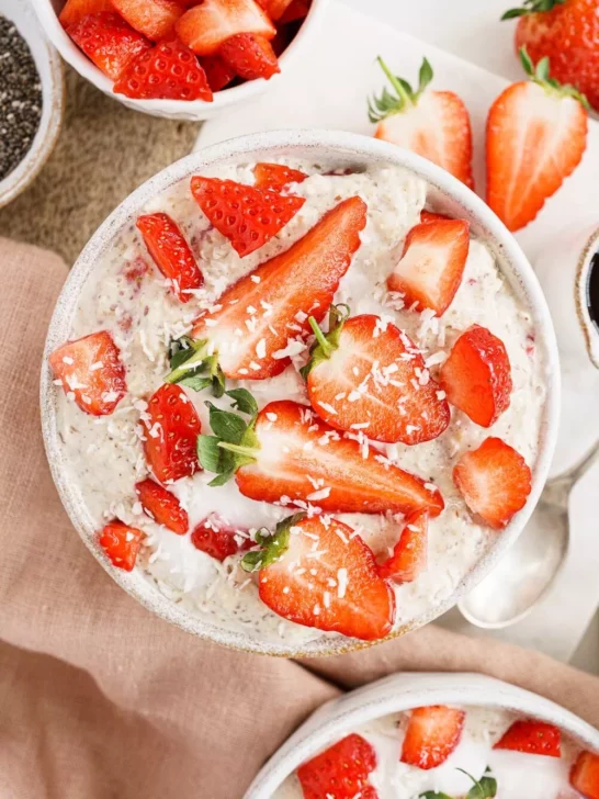 Overnight oats topped with strawberries and surrounded by strawberries. 