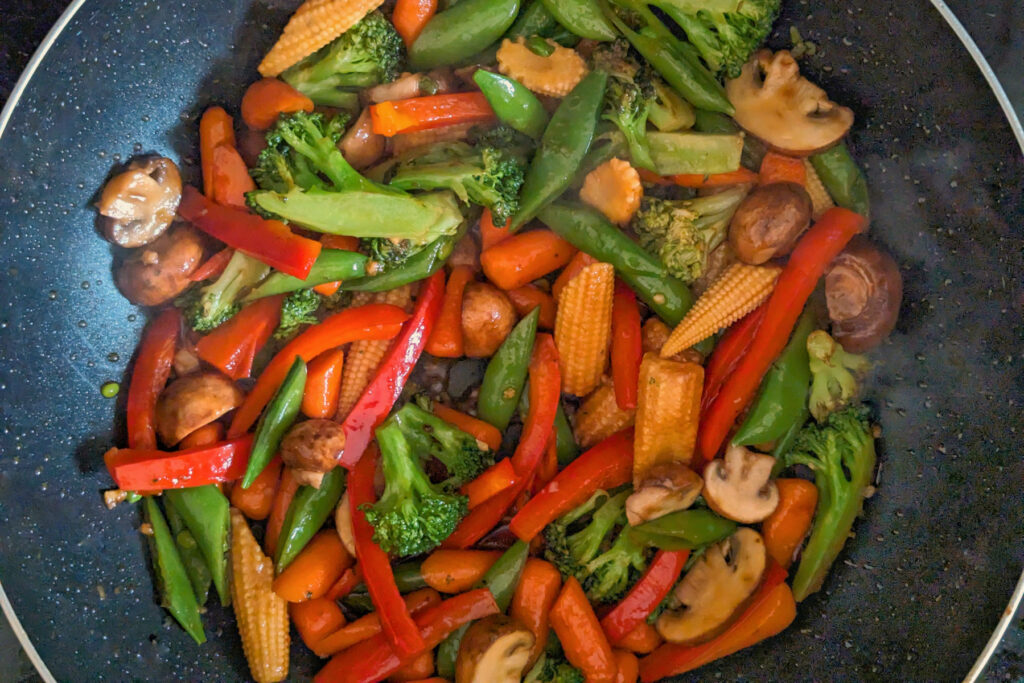 Vegetables cooking in sauce in a wok.